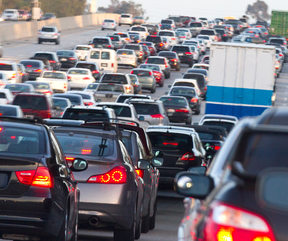 heavy traffic on a multi-lane highway, with numerous vehicles, including cars and trucks, moving slowly or at a standstill.